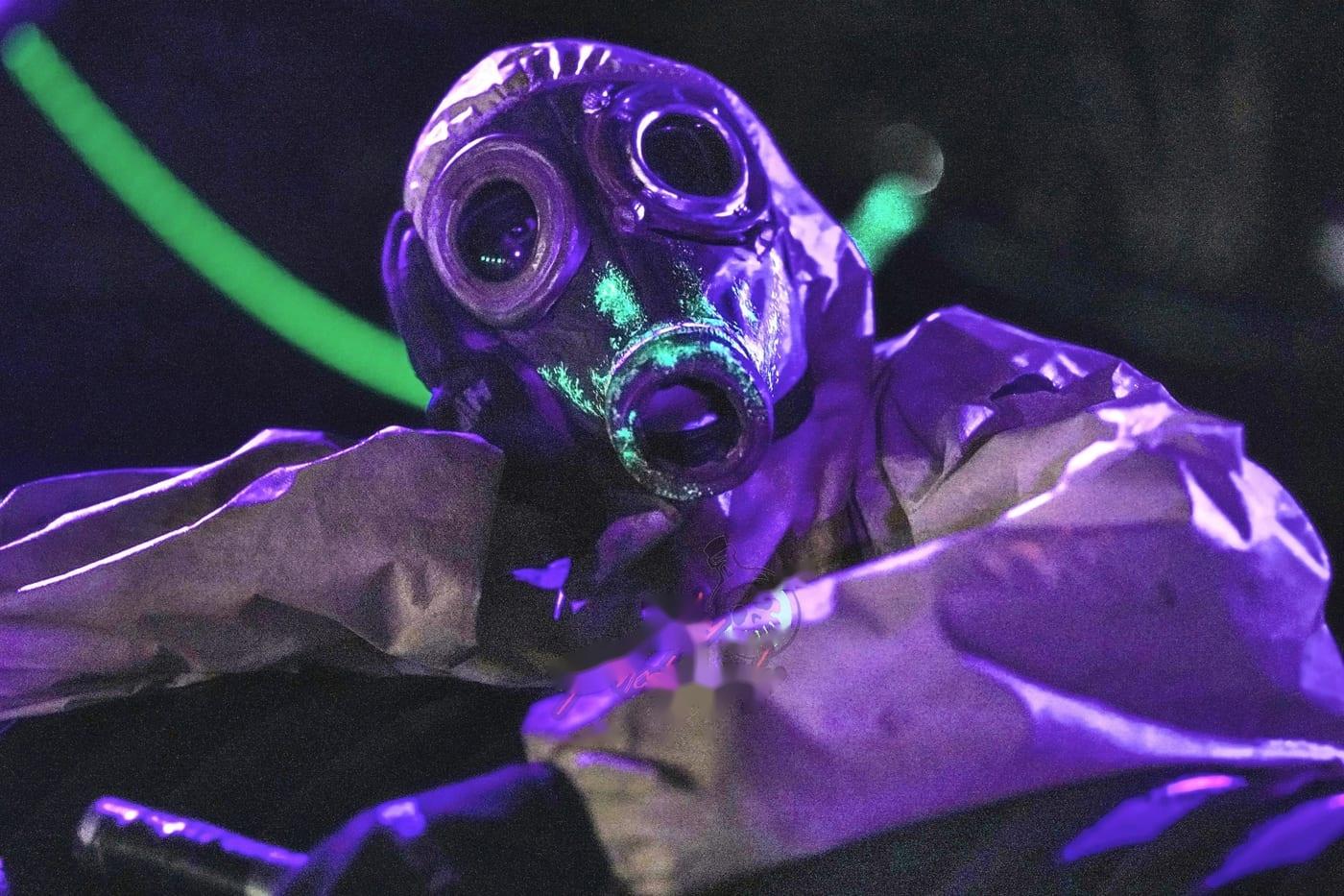 A dreadlocked character reaching toward the camera under purple light