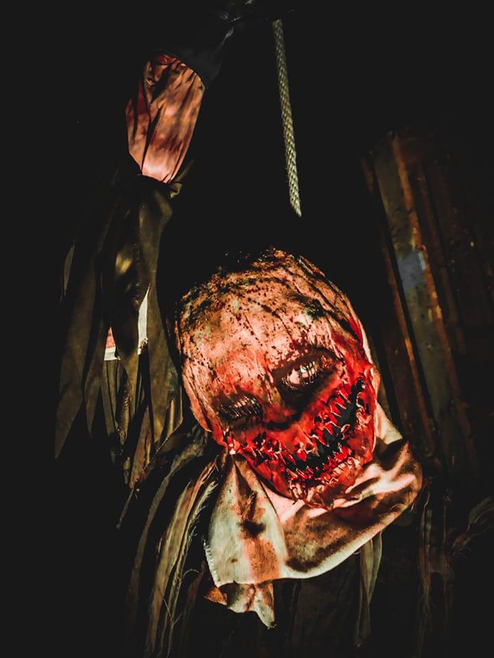 A bloodied figure hanging in the dark