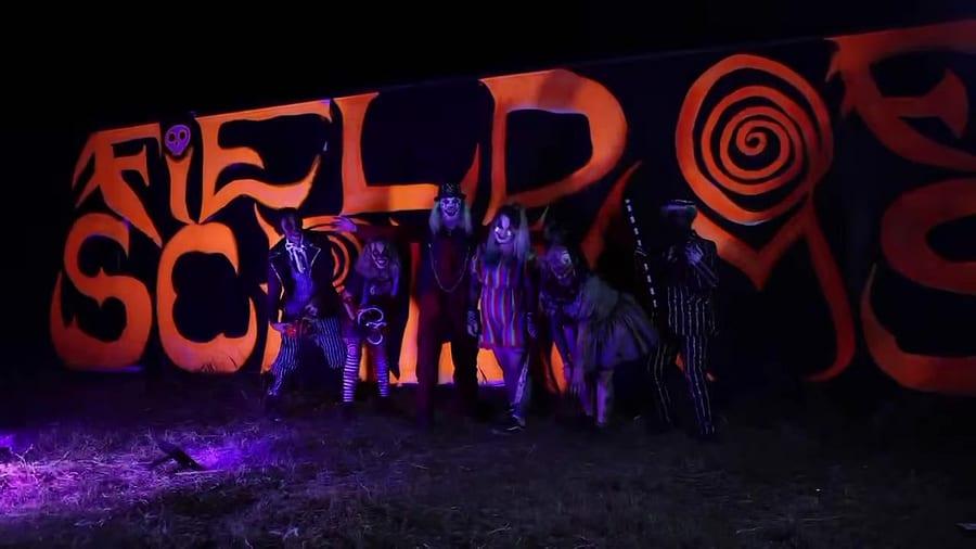 The full cast lined up in front of the Field of Screams sign